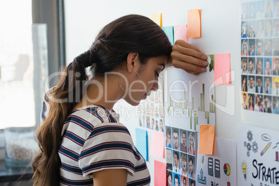 Tired businesswoman by sticky notes at office