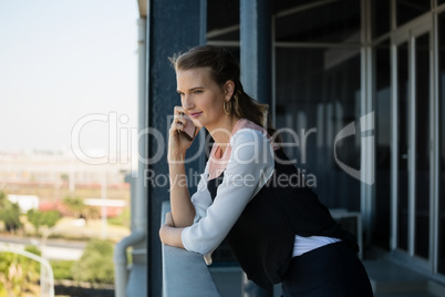 Young woman talking on mobile phone in balcony at office