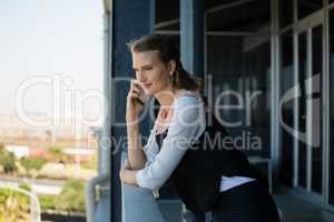 Young woman talking on mobile phone in balcony at office