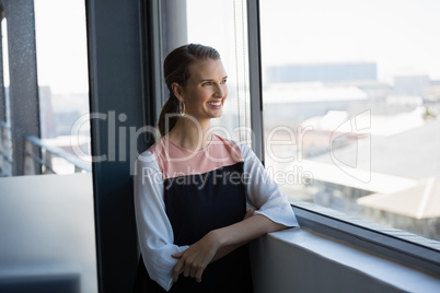 Smiling woman looking through window at office