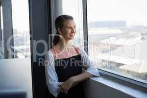 Smiling woman looking through window at office