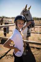 Smiling girl touching the horse in the ranch