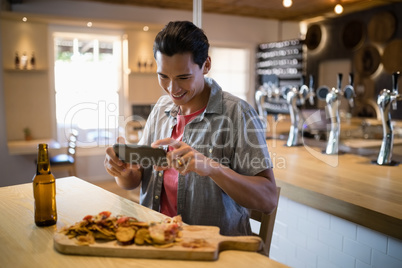Smiling man taking a picture of food on his mobile phone