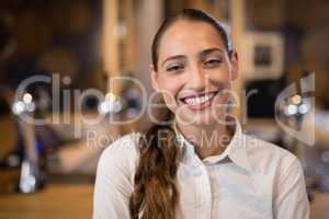 Smiling female bartender standing in bar
