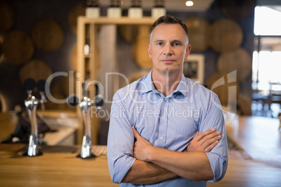 Man standing with arms crossed near bar counter