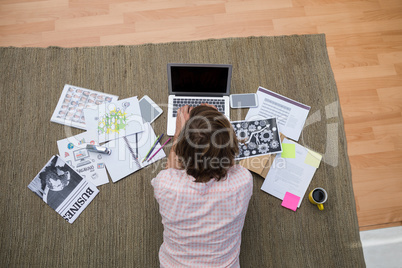 Male executive using laptop while lying on carpet