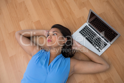 Female executive relaxing with hands behind head on the floor