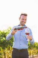 Smiling man pouring red wine from bottle in glass