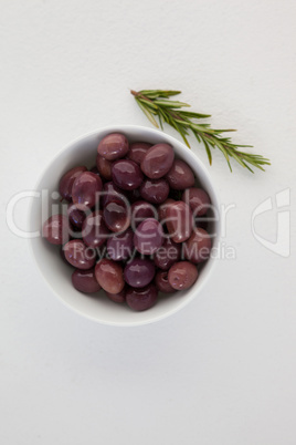 Overhead view of brown olives in bowl by herb