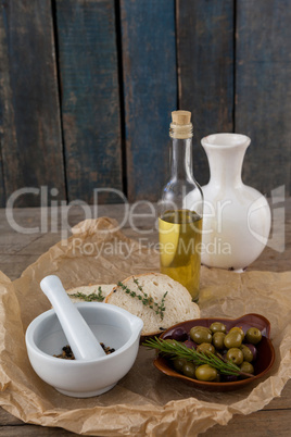 High angle view of olives with oil bottle and bread by spices in mortar pestle on table