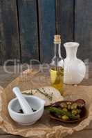 High angle view of olives with oil bottle and bread by spices in mortar pestle on table