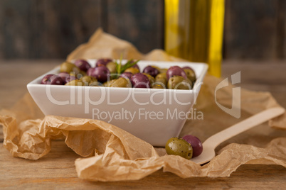 Close up of olives served in bowl by wooden spoon