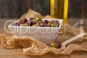 Close up of olives served in bowl by wooden spoon