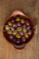 Overhead view of olives with oil in wooden container