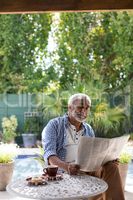 Senior man reading newspaper at table