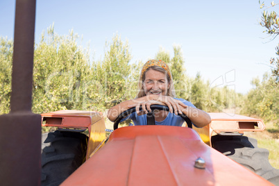 Portrait of happy woman sitting in tractor