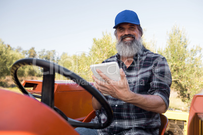 Portrait of happy man using digital tablet in tractor