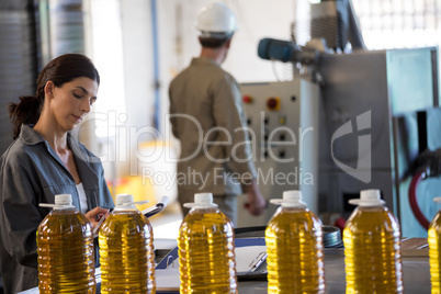 Female worker maintaining record while technician operating machine