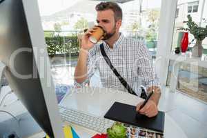 Designer having drink writing on graphics tablet