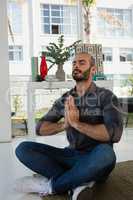 Businessman in prayer position meditating while sitting on floor