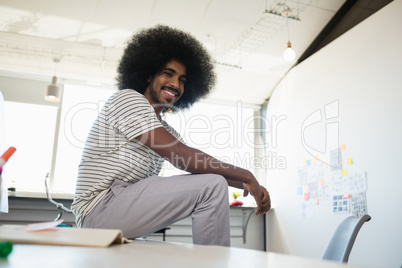 Portrait of smiling man relaxing on desk in creative office