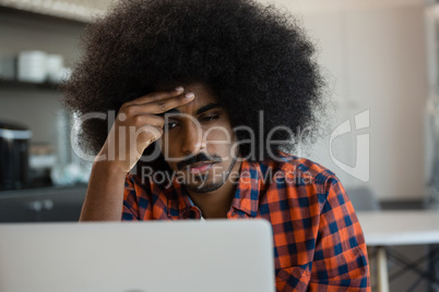 Tired man looking into laptop at office