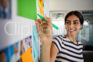 Smiling woman writing on sticky note in office