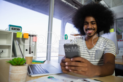 Smiling man using phone in office