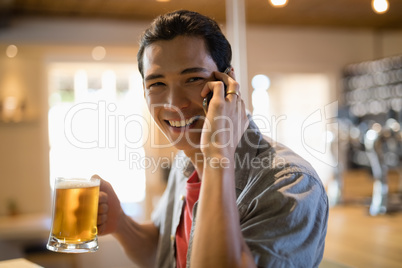 Man having beer while talking on mobile phone in a restaurant