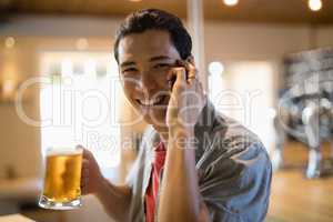 Man having beer while talking on mobile phone in a restaurant
