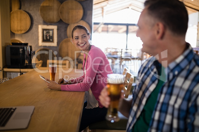 Friends interacting with each other while having glass of beer