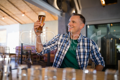 Smiling man having glass of beer at counter