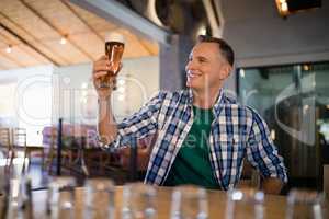 Smiling man having glass of beer at counter