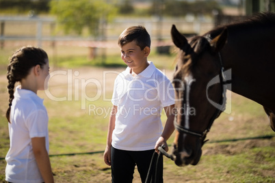 Boy and girl standing with a horse and talking