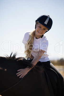 Smiling girl riding a horse in the ranch