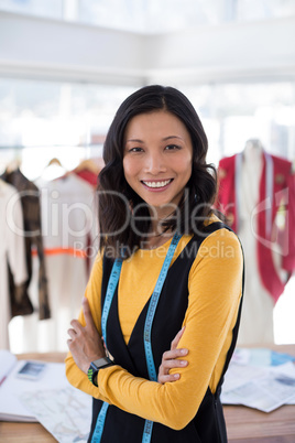 Smiling fashion designer standing with arms crossed in office