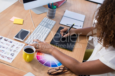 Female executive working over graphic tablet at her desk