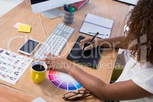 Female executive working over graphic tablet at her desk