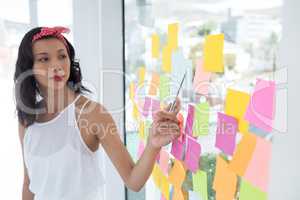 Female executive pointing at sticky note in office