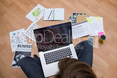 Male executive using laptop while sitting on floor