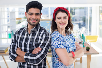 Couple standing together with arms crossed in the office