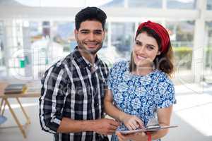 Couple discussing over clipboard in the office