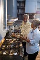 High angle view woman showing tablet computer to man while preparing food