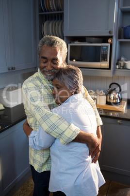 Affectionate couple embracing while standing in kitchen