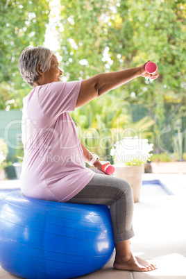 Side view of senior woman lifting dumbbells while exercising