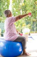 Side view of senior woman lifting dumbbells while exercising