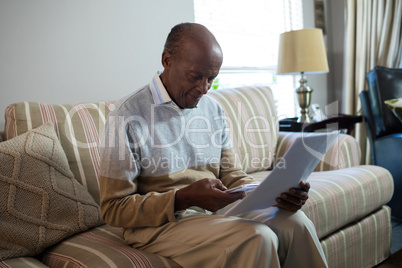 Senior man using phone while holding document
