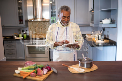 Smiling man using tablet computer while cooking food