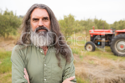 Happy man standing with arms crossed in olive farm