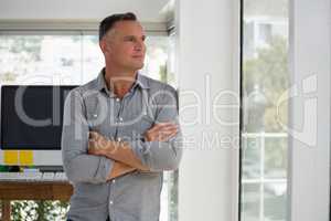Confident businessman looking through window while leaning on wall
